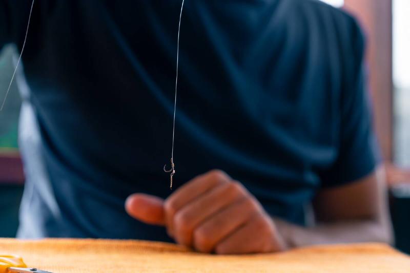 close-up of a man holding a fishing line or fly on feeder hook for freestyle fishing