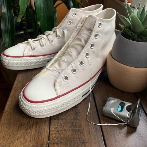 A pair of shoes, one laced with dental floss, still conntected to the container it came in.