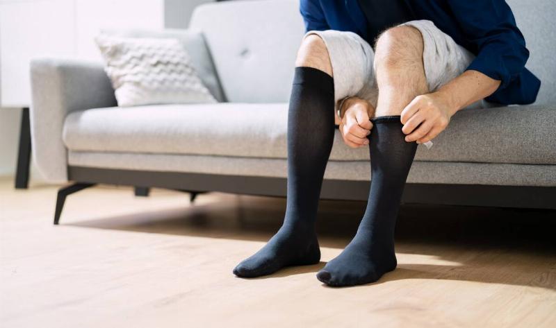 A person pulling on a pair of compression socks.