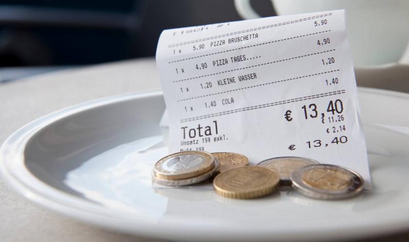 A plate with a restaurant bill and some Euro coins.