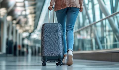A woman walking through an airport with a slim suitcase.