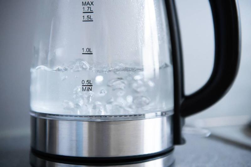Tap water boils in a kettle in a kitchen.
