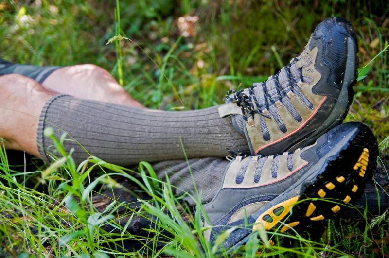 A closeup of a person's legs from the knee down as they lay in the grass, in calf socks and hiking shoes.