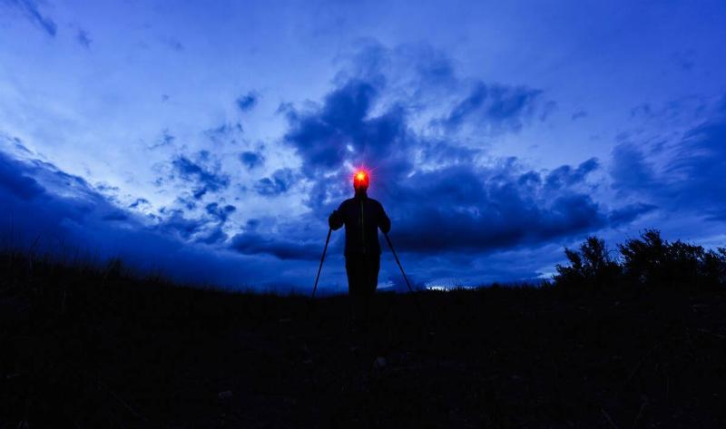 A person hiking at night with a headlamp.