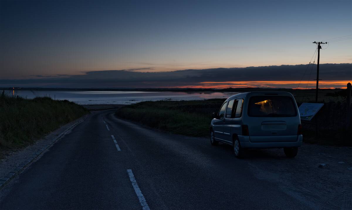 A car at miidnight waits for low tide to reveal the causeway on Lindisifarne Island on the Northumberland coast