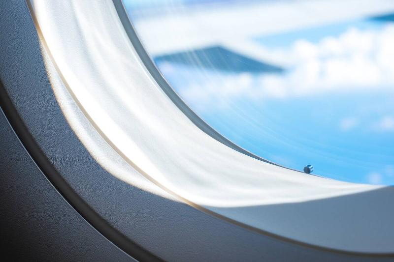 A closeup of a plane's window, showing the small hole in the bottom.