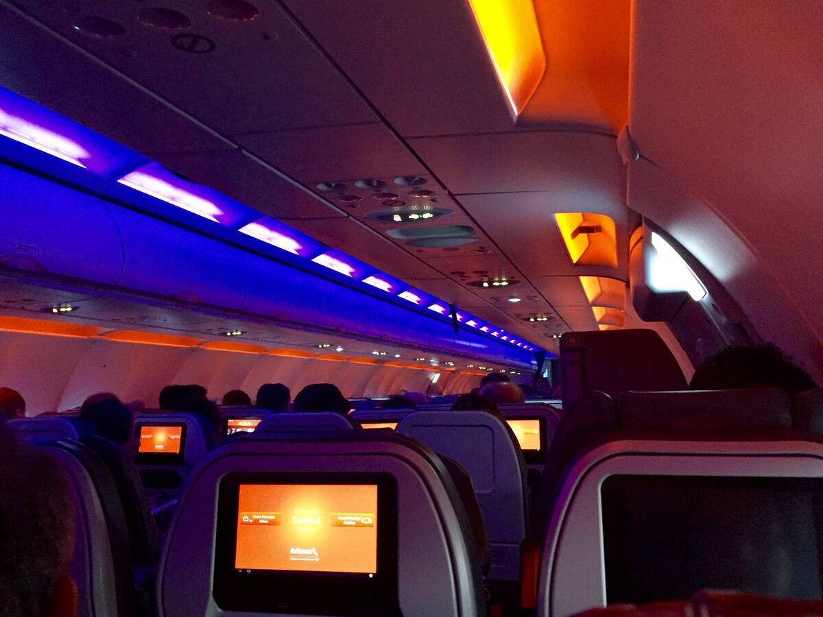 An airplane cabin with the lights dimmed.