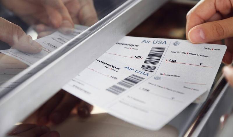 A closeup of someone handing their plane tickets to a worker.