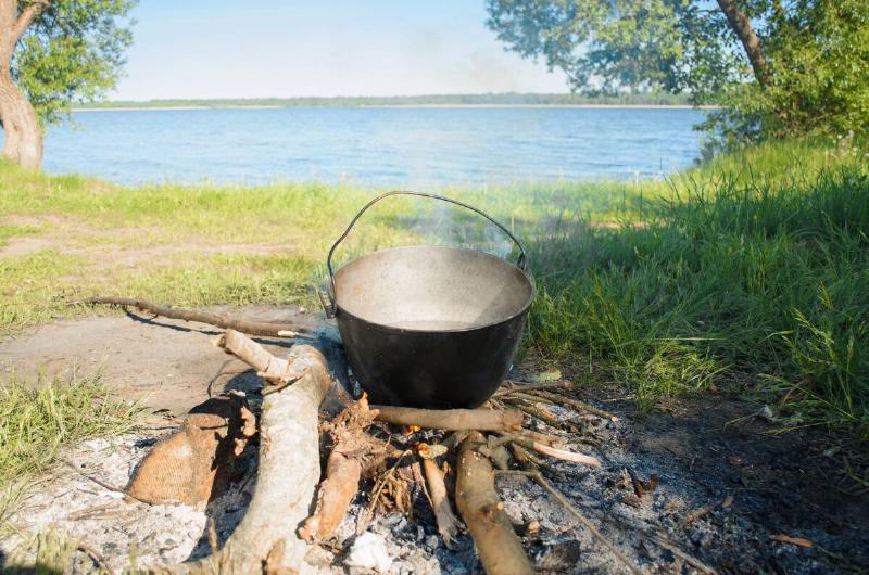 A pot of water over a campfire by a lake.