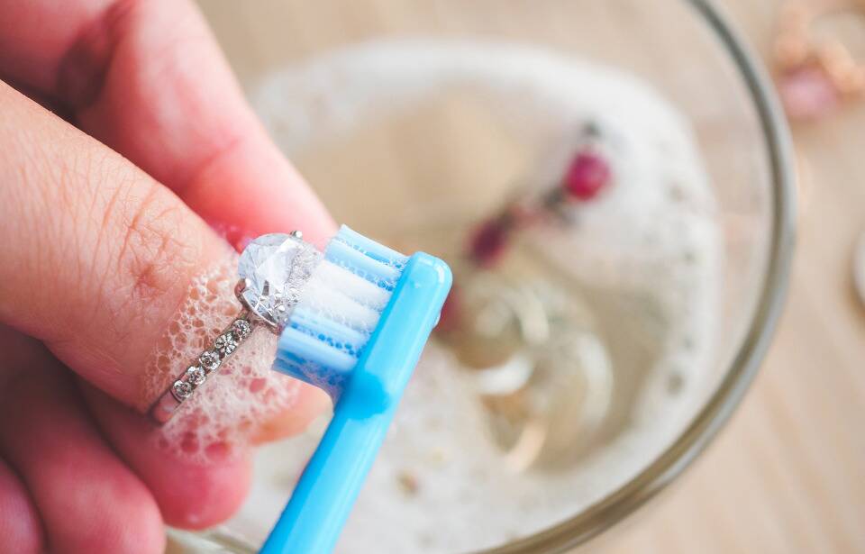 Hands cleaning a ring with a toothbrush