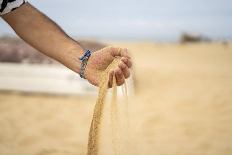 A closeup of sand running through a man's hand.