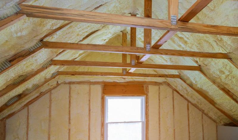 A barebones attic, the beams and insulation visible.