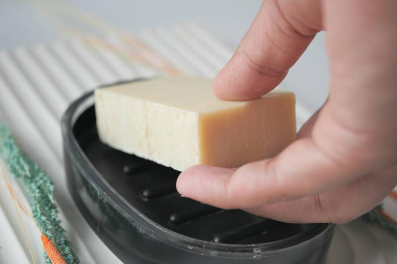 A close shot of a hand grabbing a bar of soap from its holder.