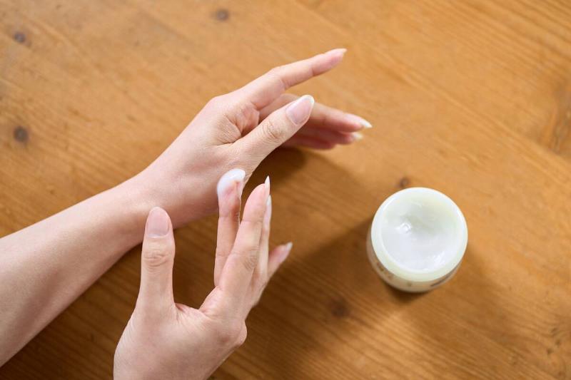 A woman applying hand cream to her hand.