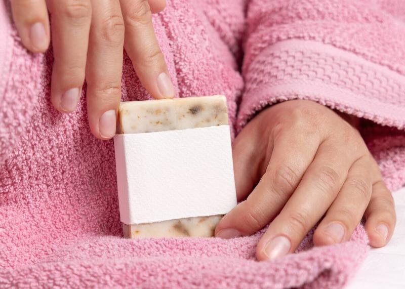 A woman holding a bar of soap, dragging her nail across the top.