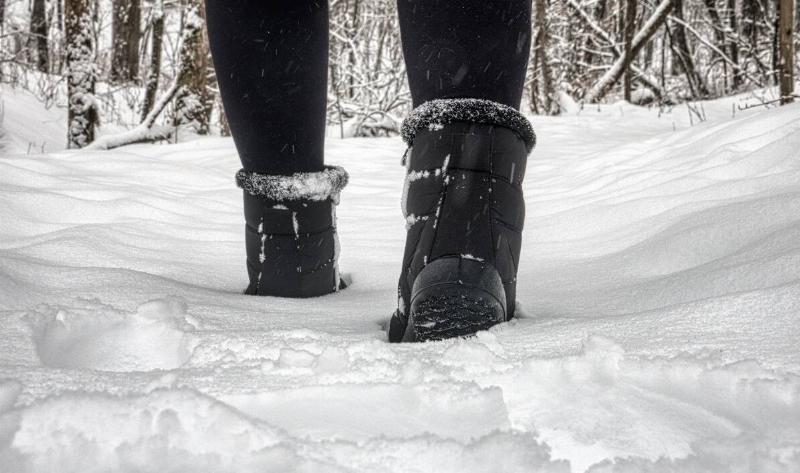 A closeup of a pair of boots as they walk through the snow.