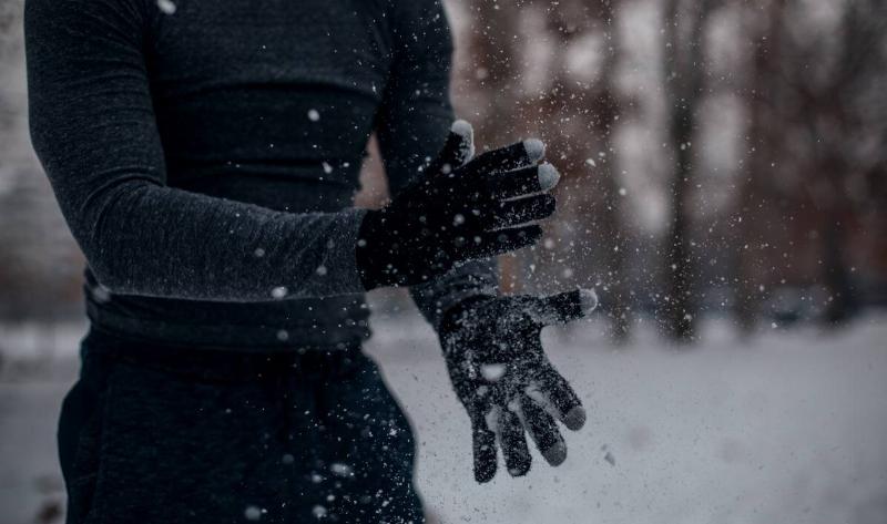 A person with gloves on dusting their hands of the snow on them.