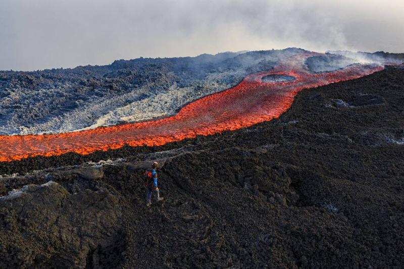 This aerial view shows a man standing near a flow of lava on the Mount  Etna volcano (Torre del Filosofo - Etna Sud) on August 28, 2025.