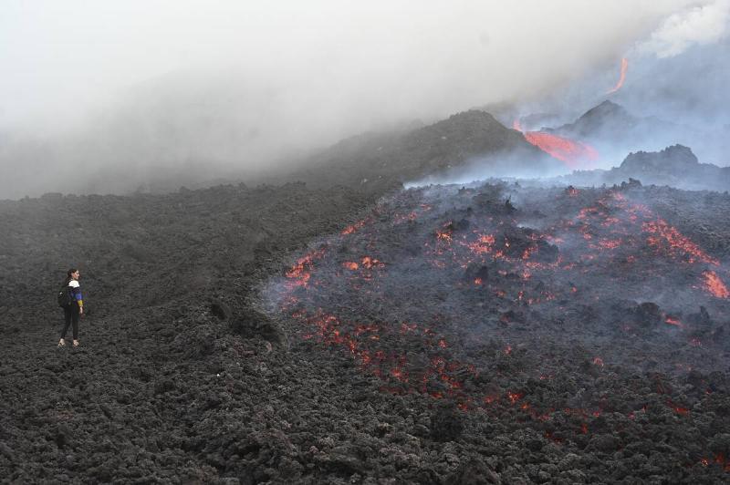 A woman watch as lava flows from Guatemala's Pacaya Volcano at the Cerro  Chino hill in San Vicente Pacaya municipality, Guatemala, on May 11, 
2021.