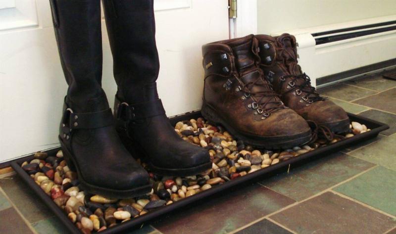 A boot tray full of rocks, two pairs of boots on it.