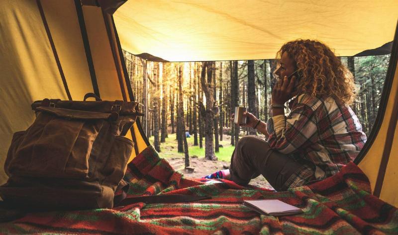 A woman taking a phone call while in her tent.
