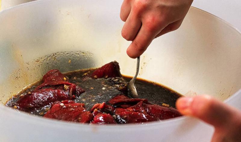Someone mixing meat in marinade.
