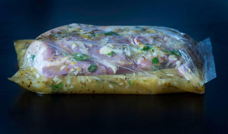 Some meat being marinated in a plastic bag.