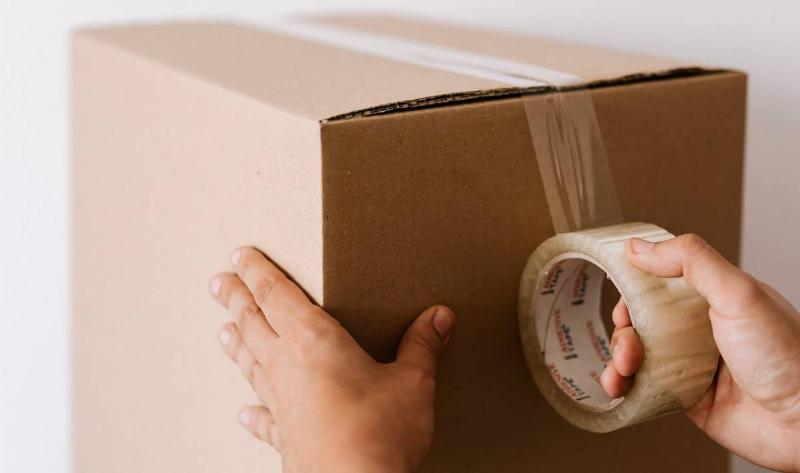 Someone taping up a cardboard box.
