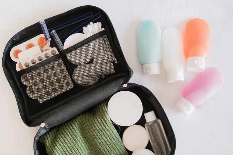 Black cosmetic travel kit on the bed. colorful cosmetic bottles, pills and hygiene items for travel