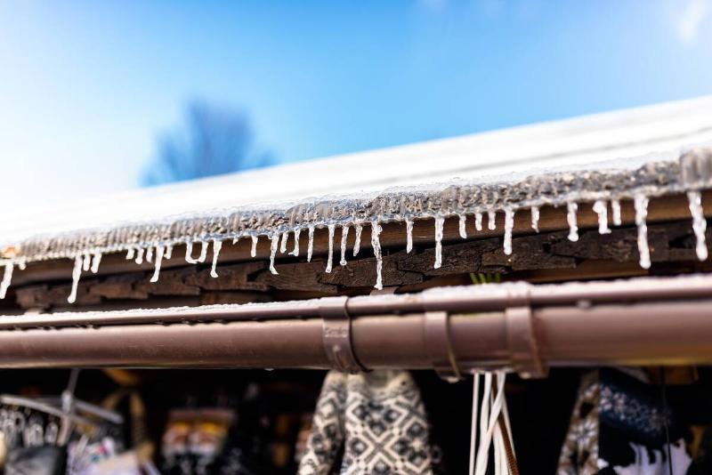 Small icicles hanging off a roof above a gutter pipe.