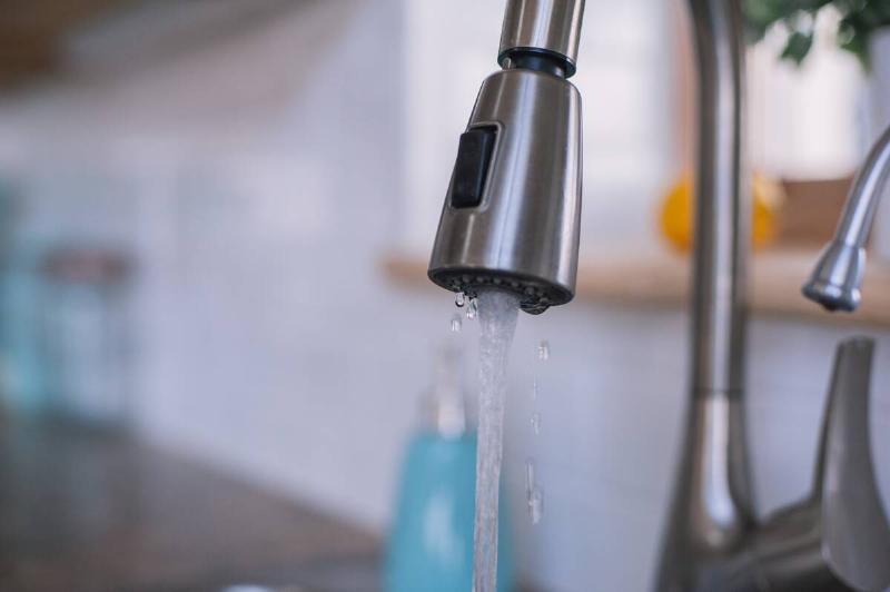 A kitchen sink faucet running weakly.