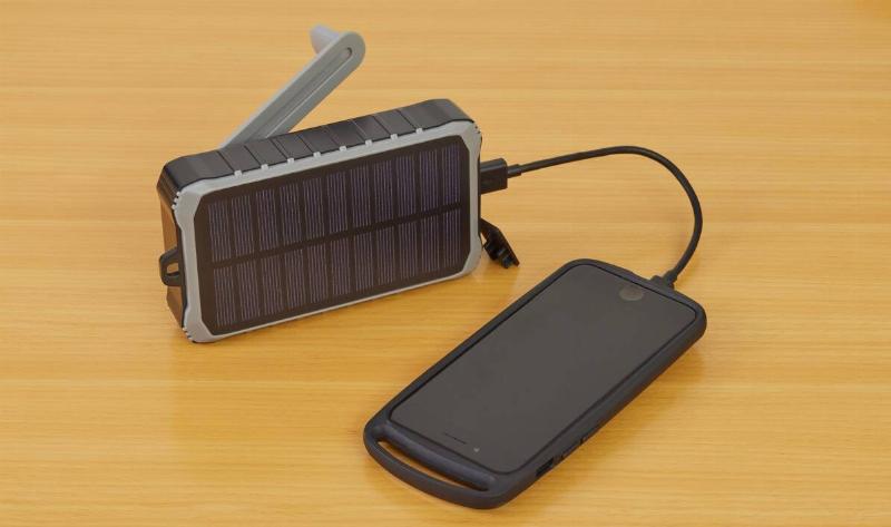 A solar charger charging a phone on a table.