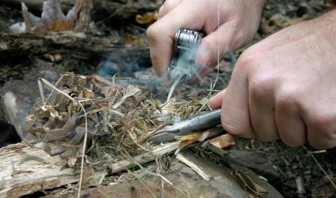 A closeup of someone starting a fire with some kindling.