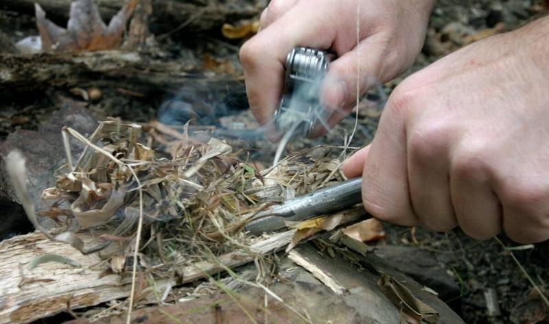 A closeup of someone starting a fire with some kindling.