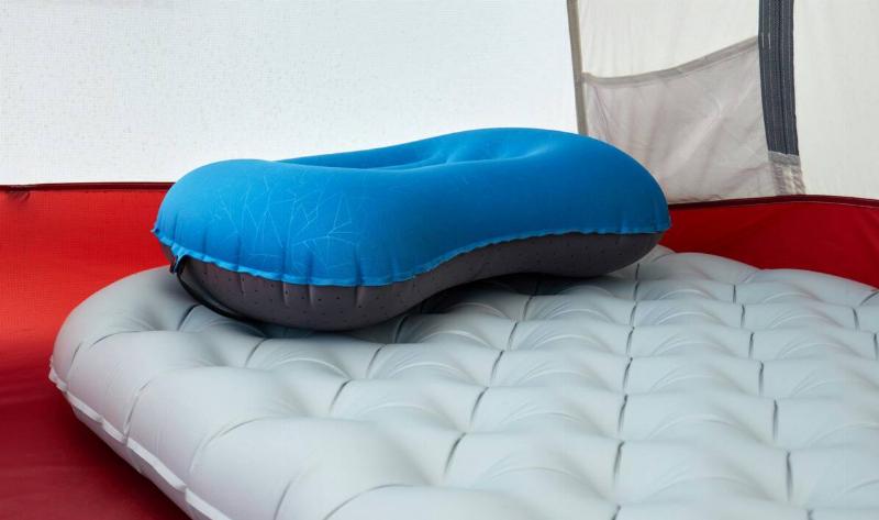 An inflatable pillow atop an inflatable mattress in a tent.