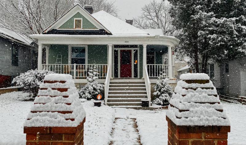A home in winter, the walkway and yard covered in snow.