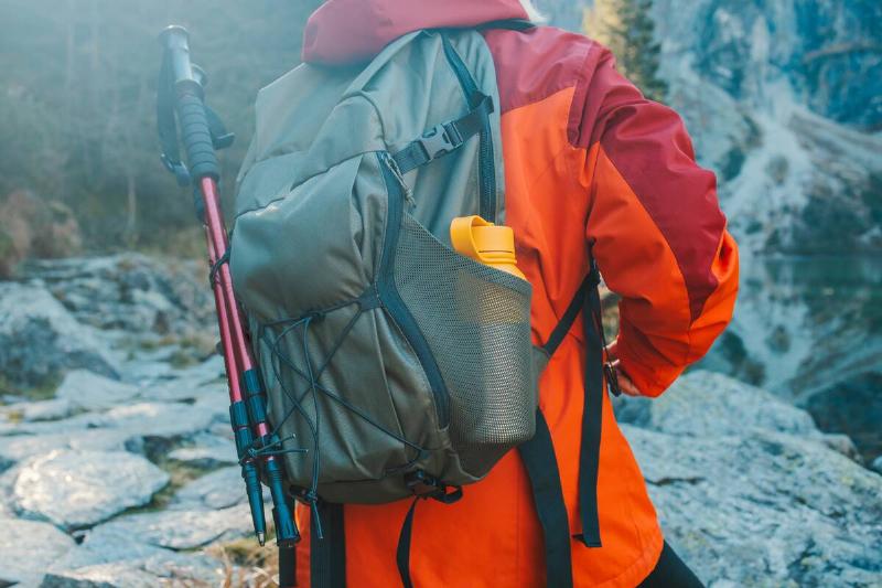 Lady tourist with a backpack standing on top of the mountain and enjoy the beautiful view of mountains Morskie Oko lake. Hiking travel and adventure in Poland, Tatry