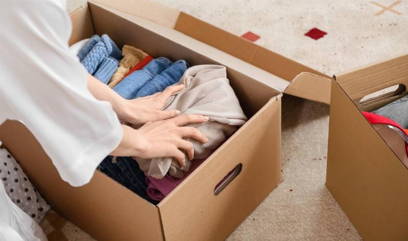 A person packing clothes into a box.