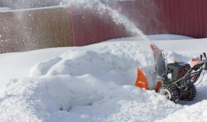 A person pushing a gas snowblower.