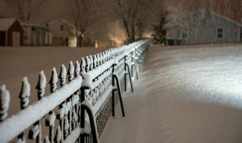 A metal fence with snow on it.