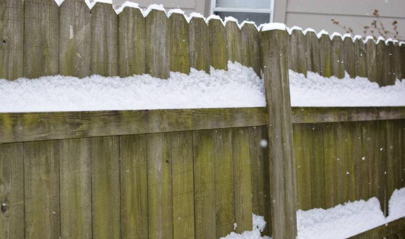 A wooden fence with snow on it.