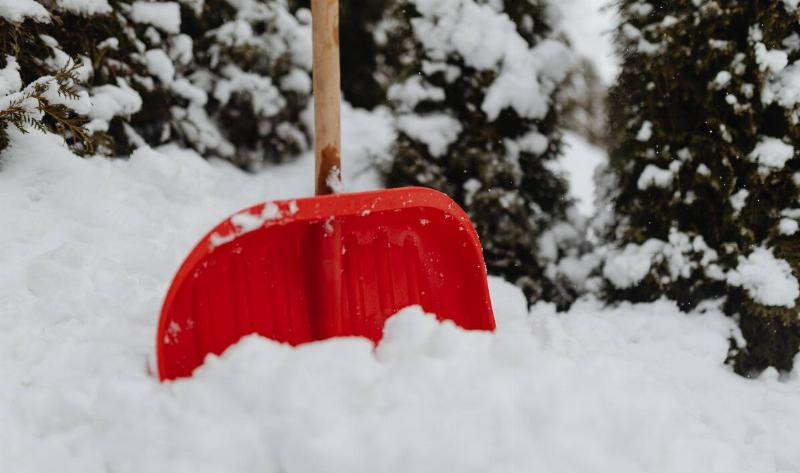 A red plastic snow shovel stuck in a snowbank.