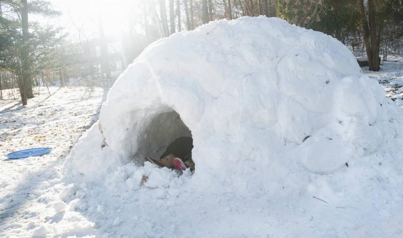 A homemade igloo-like structure, someone's boots visible inside.