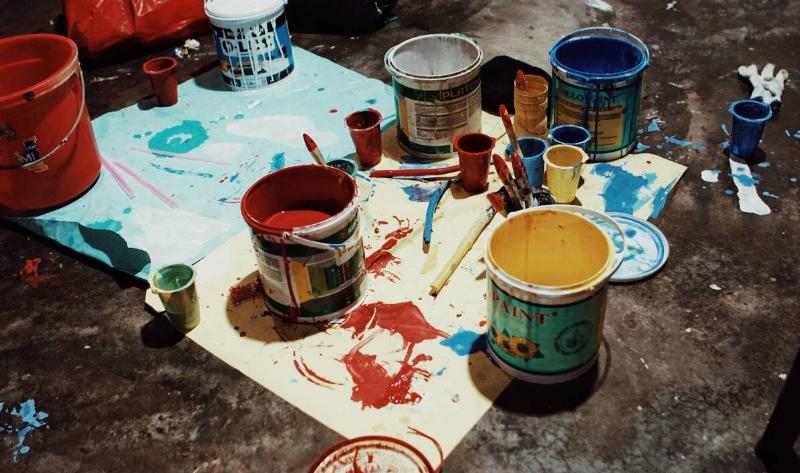 Paint cans open on a tarp.