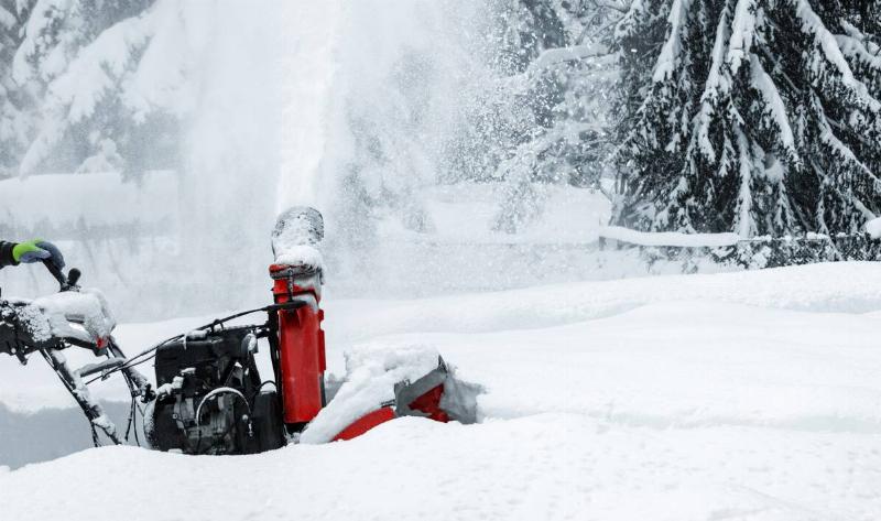 A snowblower being pushed through a large snowbank.