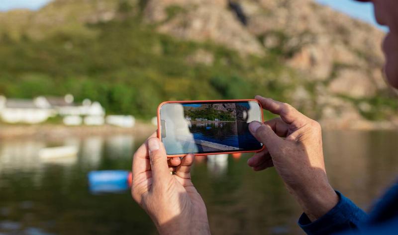 A person raising their phone to take a photo of the landscape.