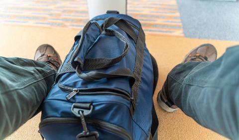 A dufflebag at someone's feet.