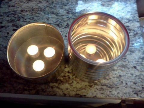 Two coffee tins, each with three lit tealights in them.