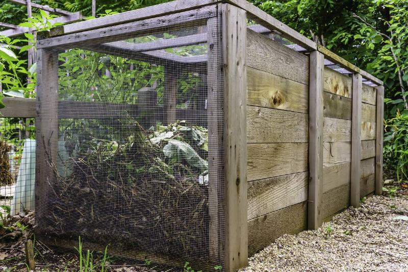A large compost box with leaves and debris in it.