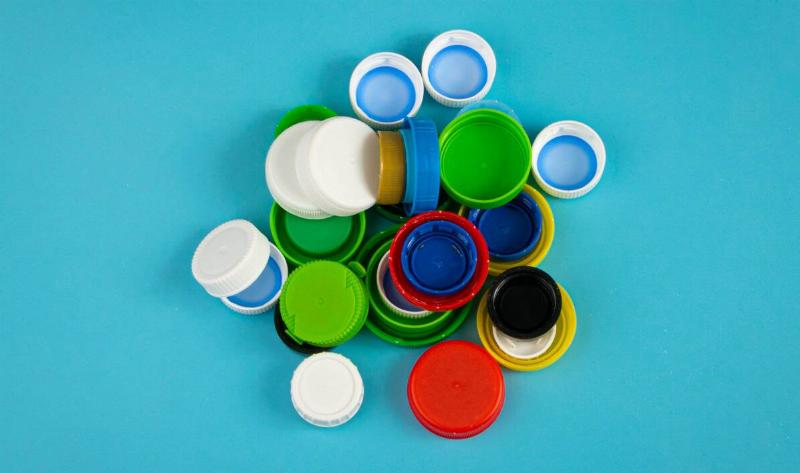 A small pile of bottle caps on a teal background.